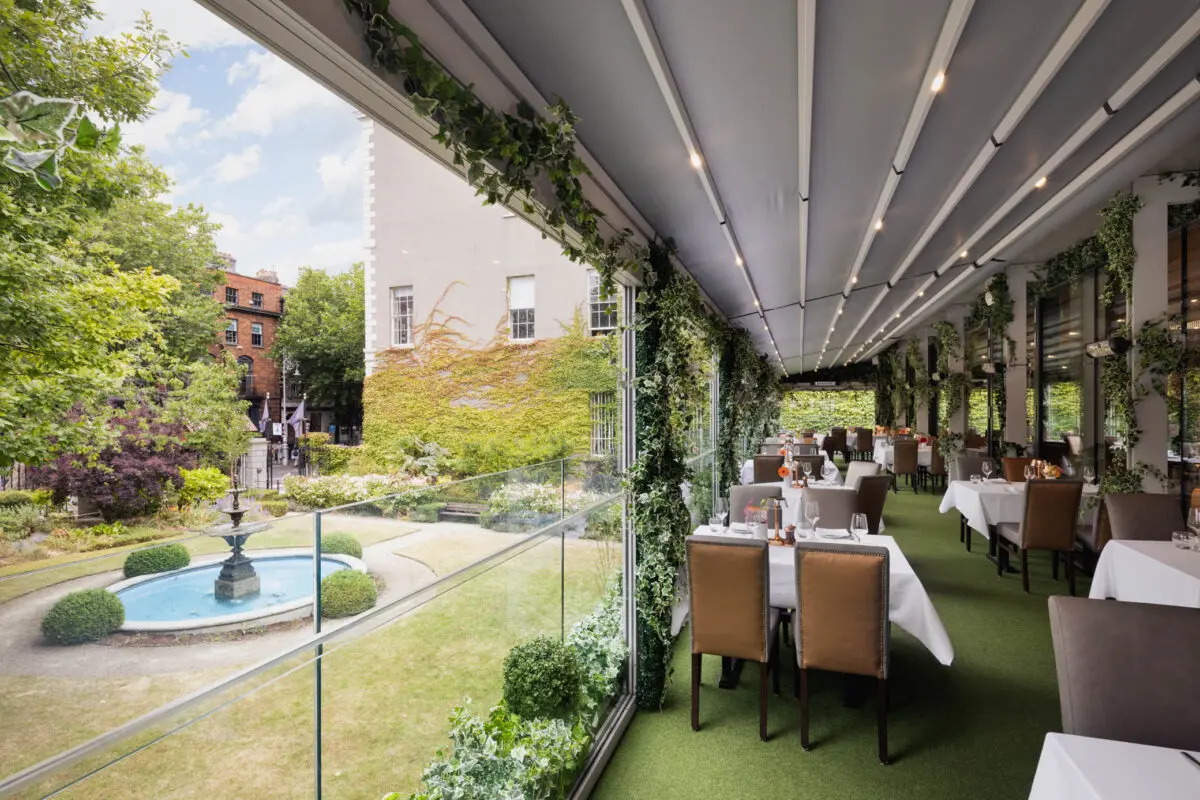 The Terrace at FIRE Steakhouse & Bar, featuring elegant outdoor dining surrounded by lush greenery. The all-weather terrace overlooks The Lord Mayor's Garden and Dawson Street.