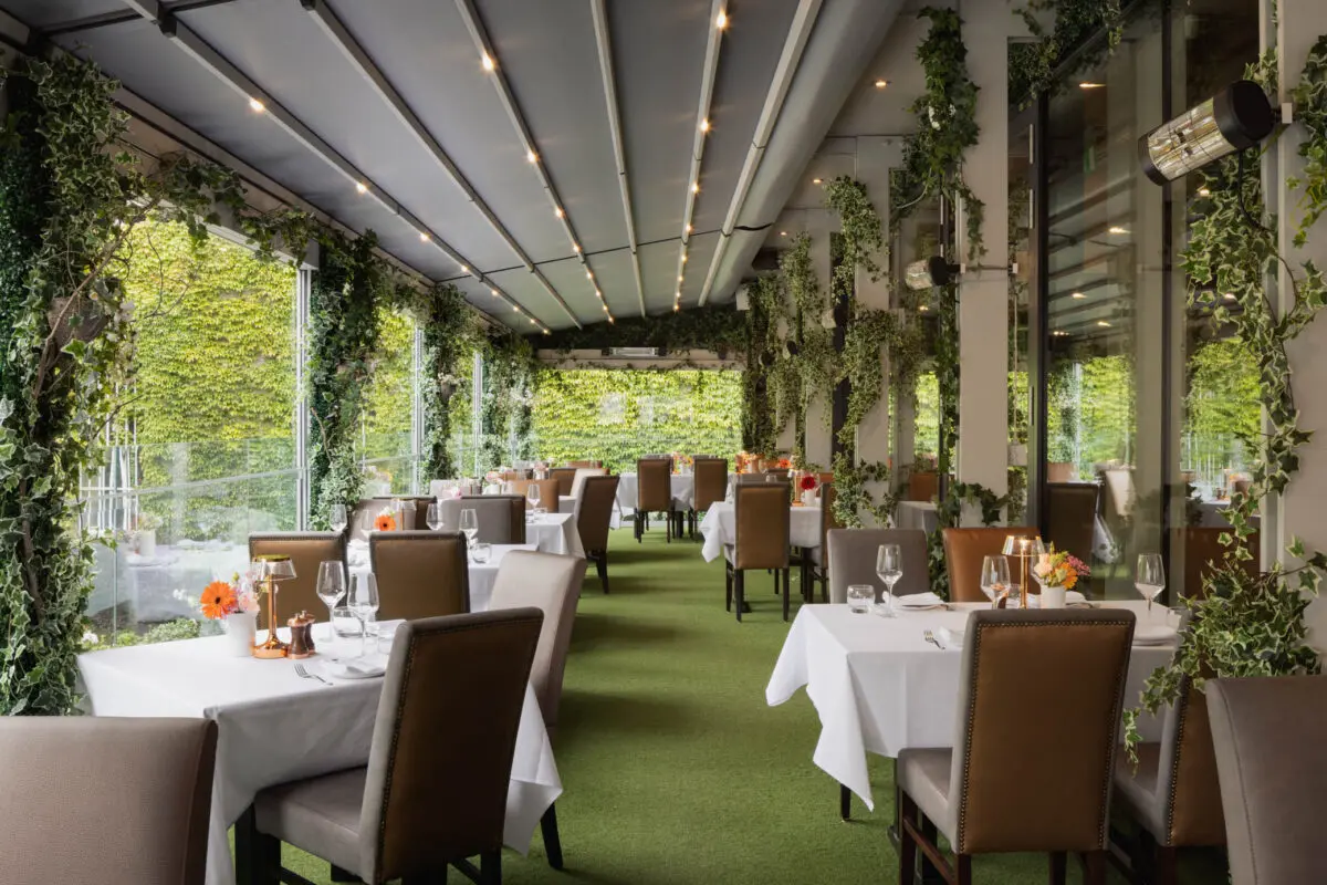 The Terrace at FIRE Steakhouse & Bar, featuring elegant outdoor dining surrounded by lush greenery. The all-weather terrace overlooks The Lord Mayor's Garden and Dawson Street.